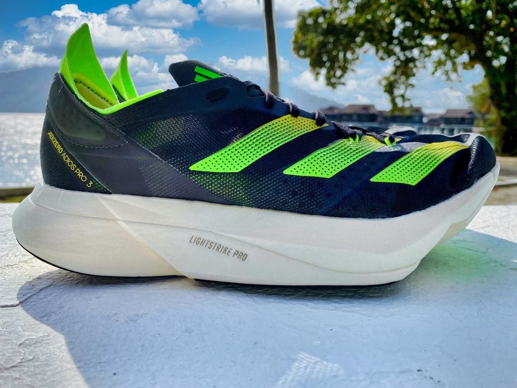 Adidas Adios Pro 3 running shoes on a scenic mountain road